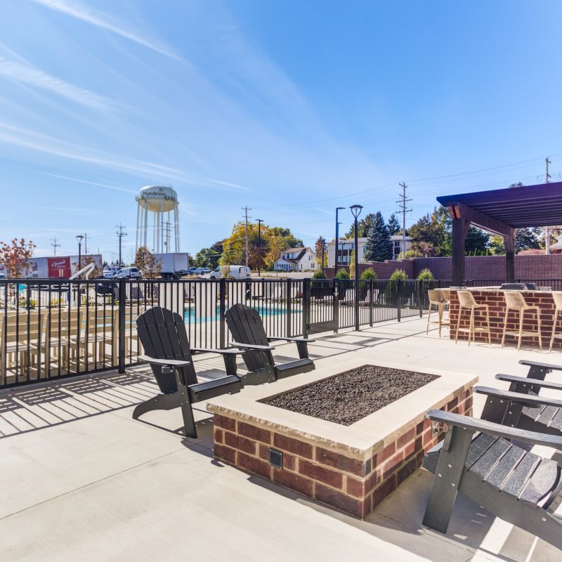 Outdoor terrace with wooden bench seating, concrete deck, metal railings, and city views at Station 250 outdoor amenities Mundelein IL