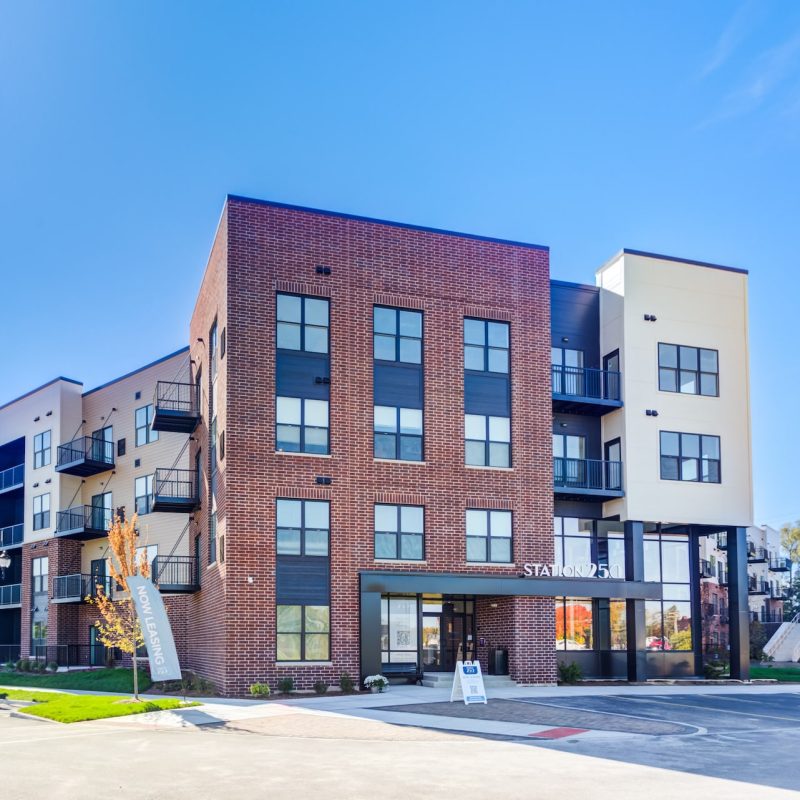 Station 250 modern apartment building front view with brick and siding exterior under blue sky in Mundelein IL