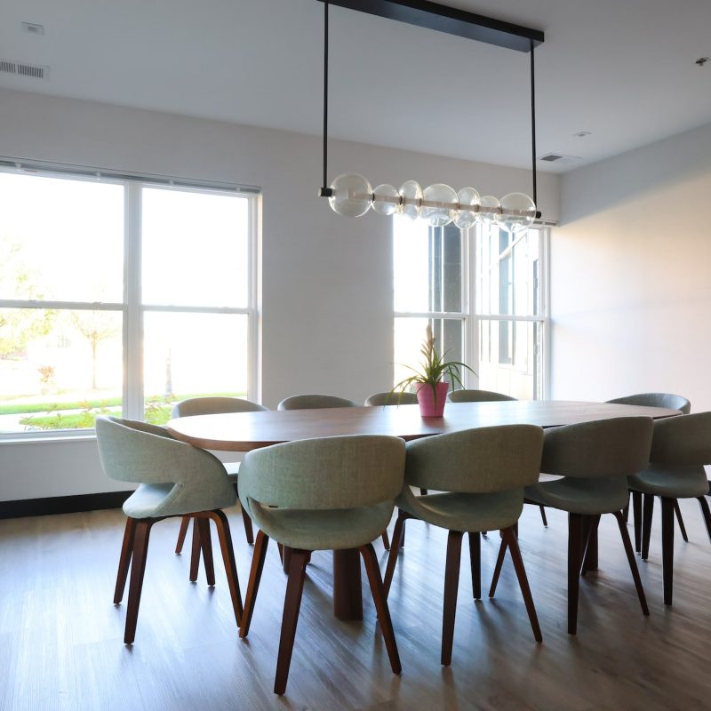 Professional boardroom with conference table for eight, upholstered chairs, modern pendant lighting, and large windows at Station 250 coworking space Mundelein IL