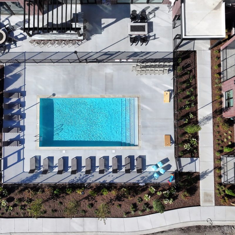Station 250 swimming pool area with modern apartment building backdrop and outdoor furniture Mundelein IL